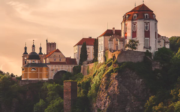 A stunning HD desktop wallpaper featuring man-made Czech Republic architecture with a historic castle perched on a rocky cliff at sunset.