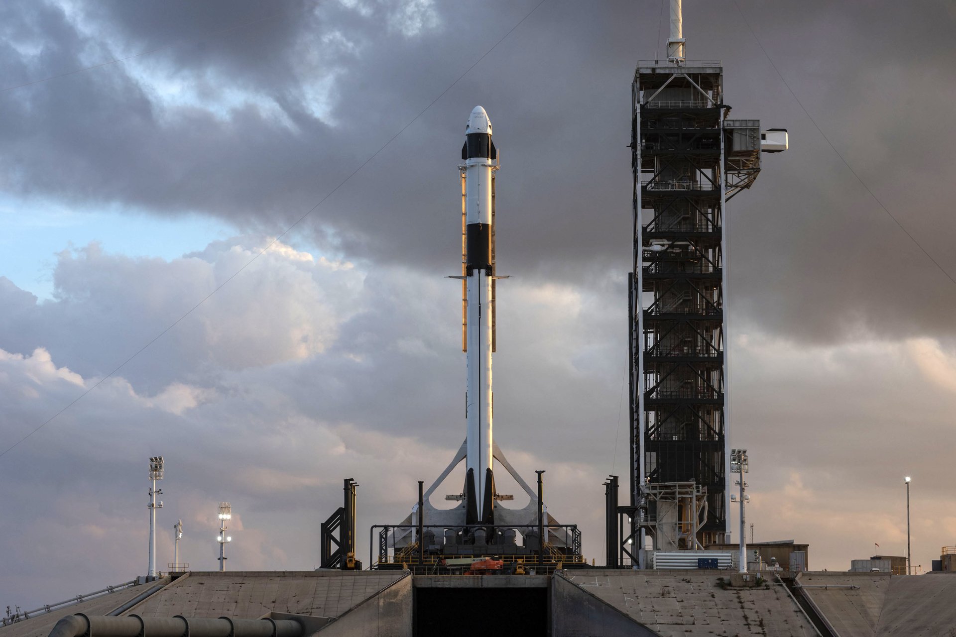 HD desktop wallpaper of SpaceX Falcon 9 rocket poised for launch at the launchpad with a cloudy sky backdrop.