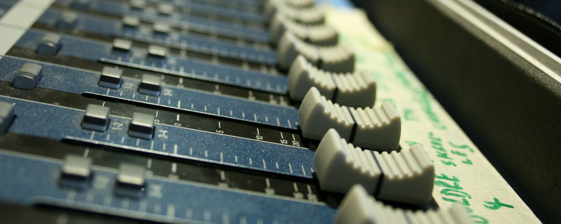 HD PC desktop wallpaper featuring a close-up of an audio mixing console with sliders and knobs, highlighting music production equipment.