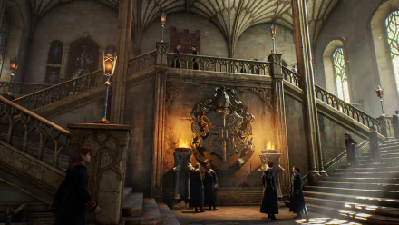 Interior view of Hogwarts Castle from the video game Hogwarts Legacy, showcasing detailed architecture and students gathered near a large crest, shown in 4K Ultra HD.