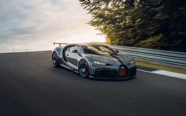 A sleek Bugatti Chiron Pur Sport supercar speeds along a racetrack at sunset, captured in stunning 4K Ultra HD for PC desktop wallpaper use.