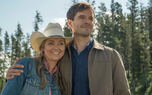 HD wallpaper of two smiling characters from the Heartland TV series, standing outdoors with trees in the background.