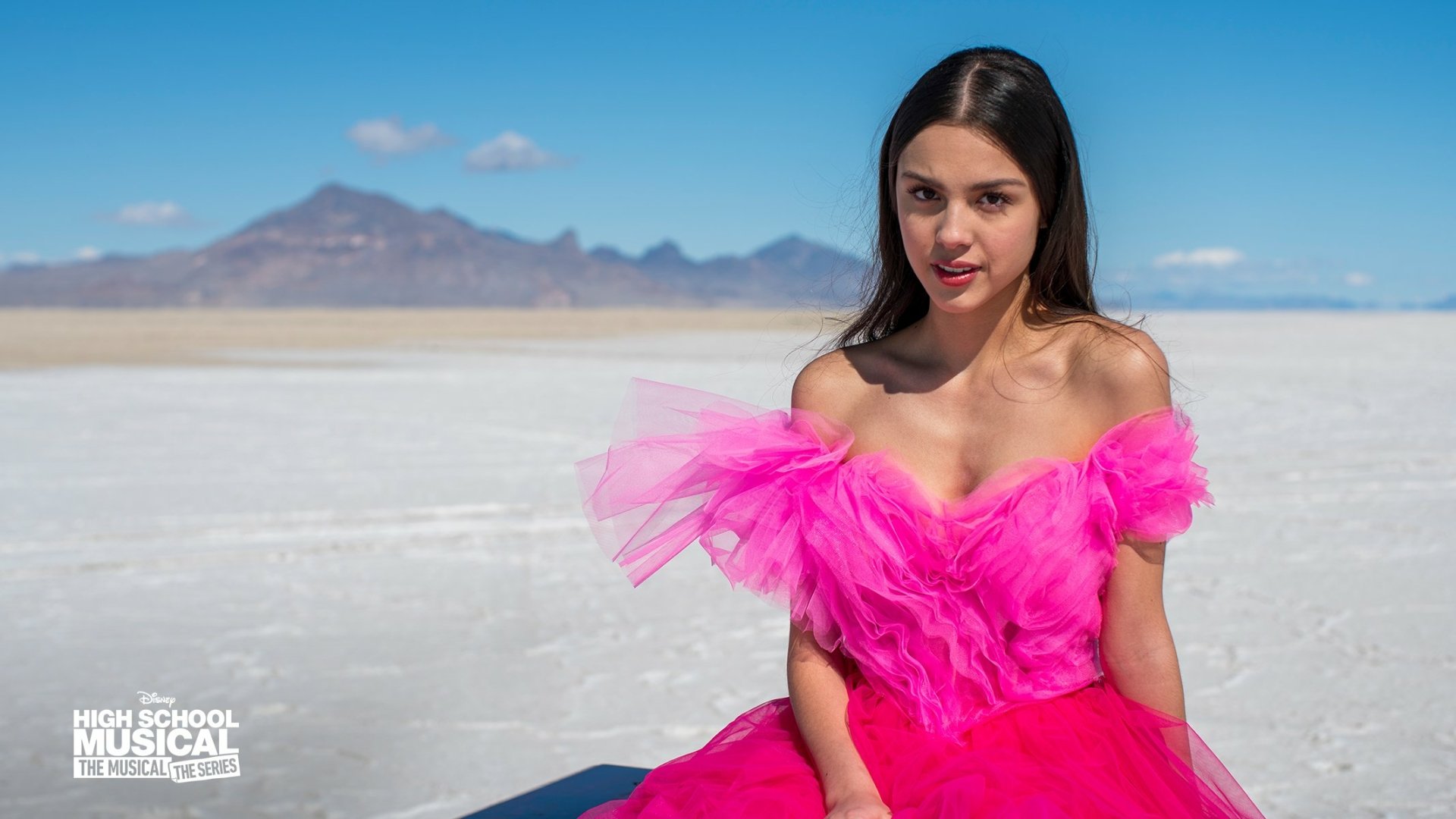 HD wallpaper featuring a character from High School Musical: The Musical: The Series, wearing a pink dress against a desert backdrop.