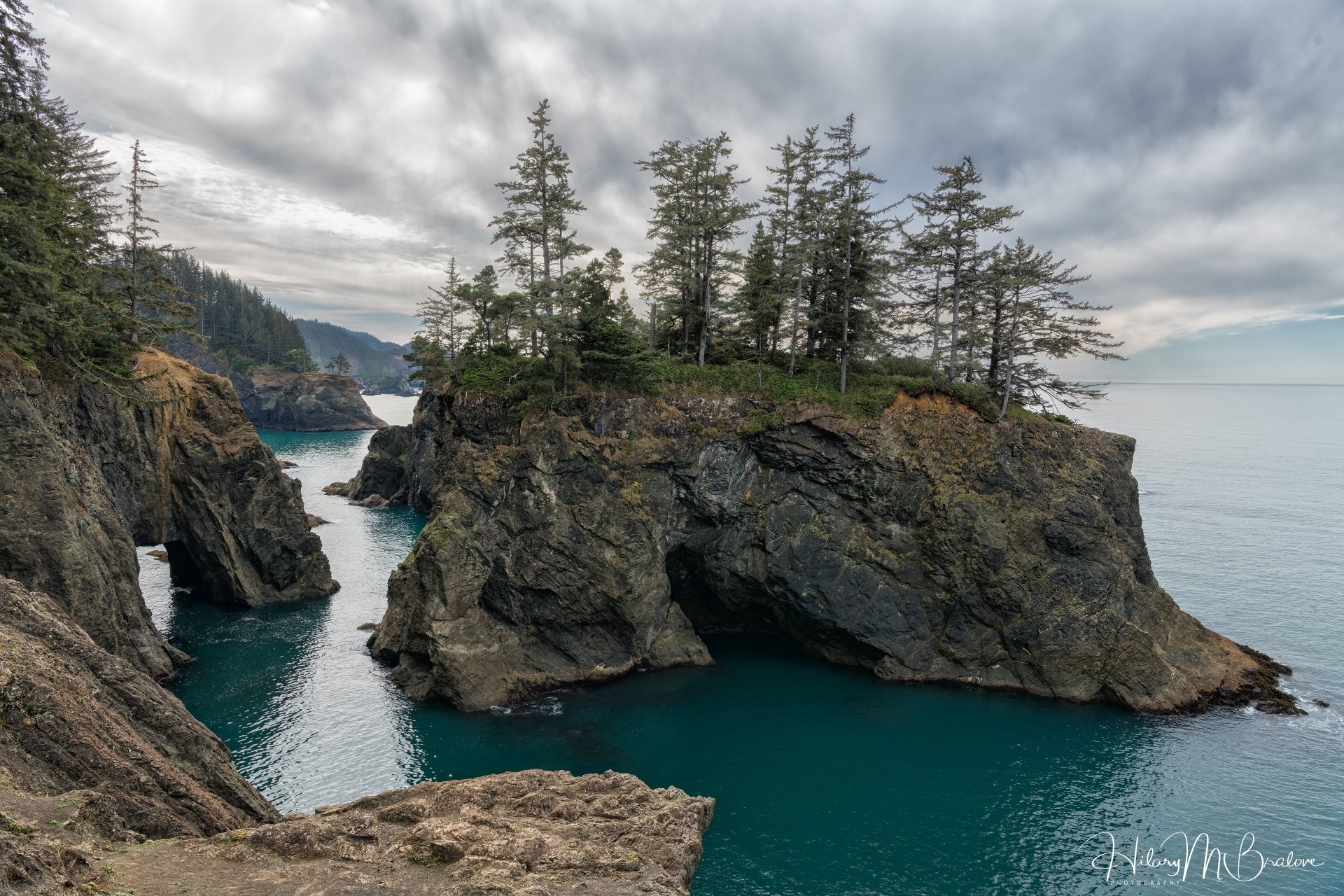 4K Ultra HD PC desktop wallpaper and background: rugged coastline with sea stacks topped by evergreens, a turquoise inlet and dramatic cloudy sky — nature, coastline