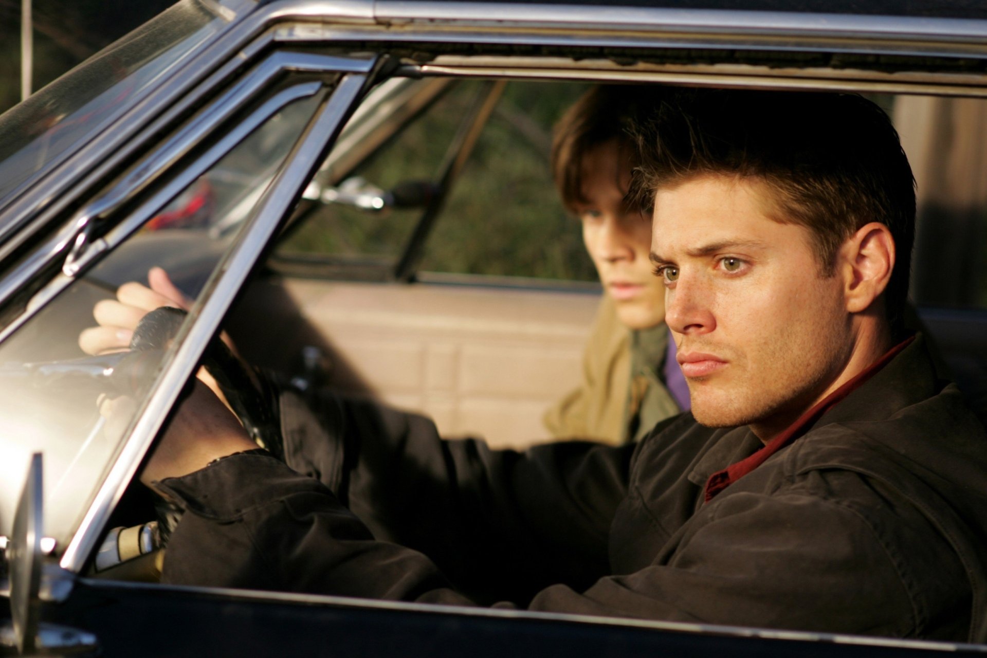 HD desktop wallpaper: close-up of two men in a car, tense expressions and moody lighting, evoking the TV show Supernatural.