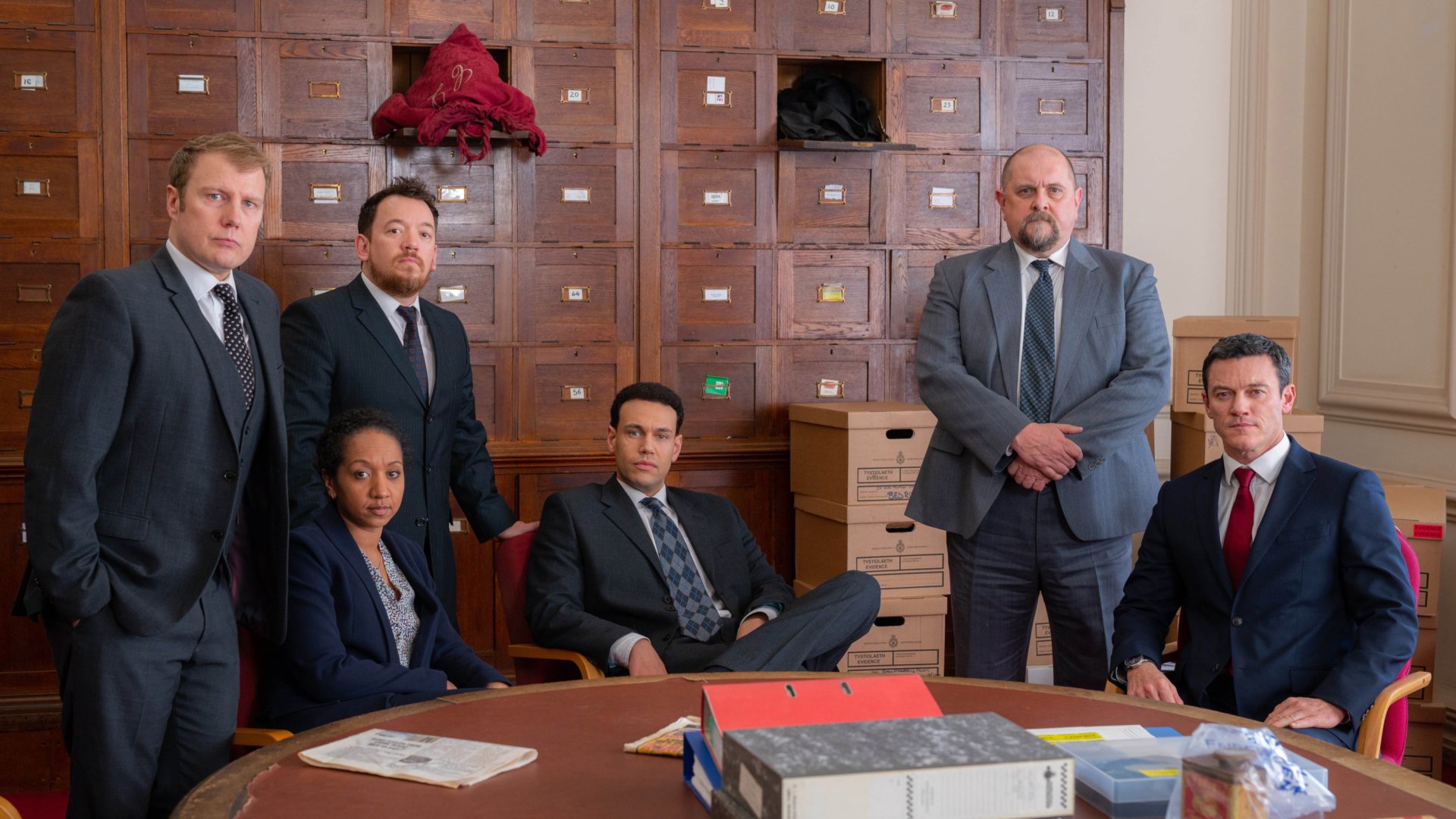 HD desktop wallpaper from The Pembrokeshire Murders featuring the cast posed solemnly in an office setting.