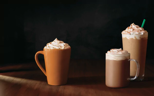 HD desktop wallpaper featuring a mug and two glasses of coffee with whipped cream on a dark background.