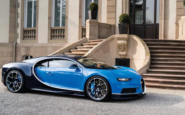 HD desktop wallpaper featuring a sleek blue Bugatti Chiron supercar parked in front of an elegant building with grand stairs and potted plants.