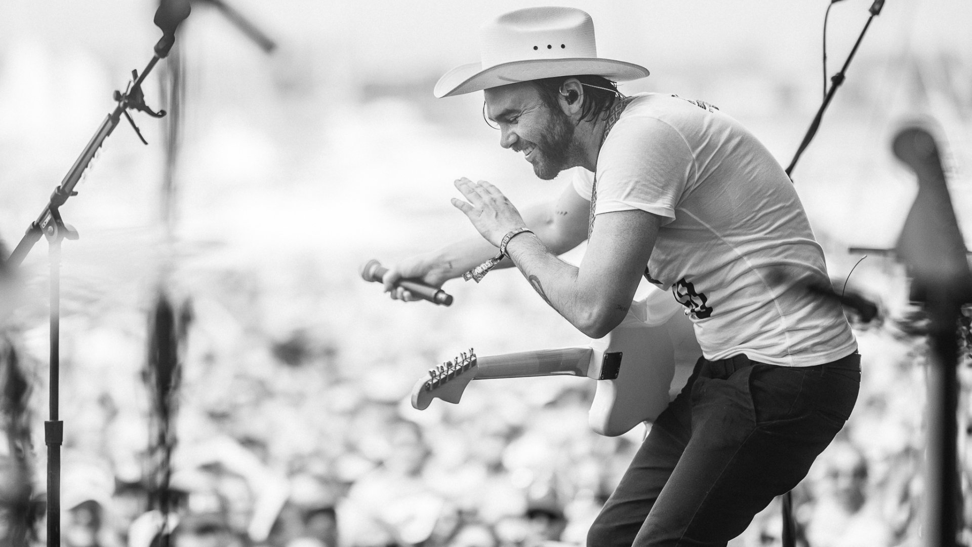 HD wallpaper featuring Shakey Graves performing live, passionately playing guitar in a hat, in monochrome.