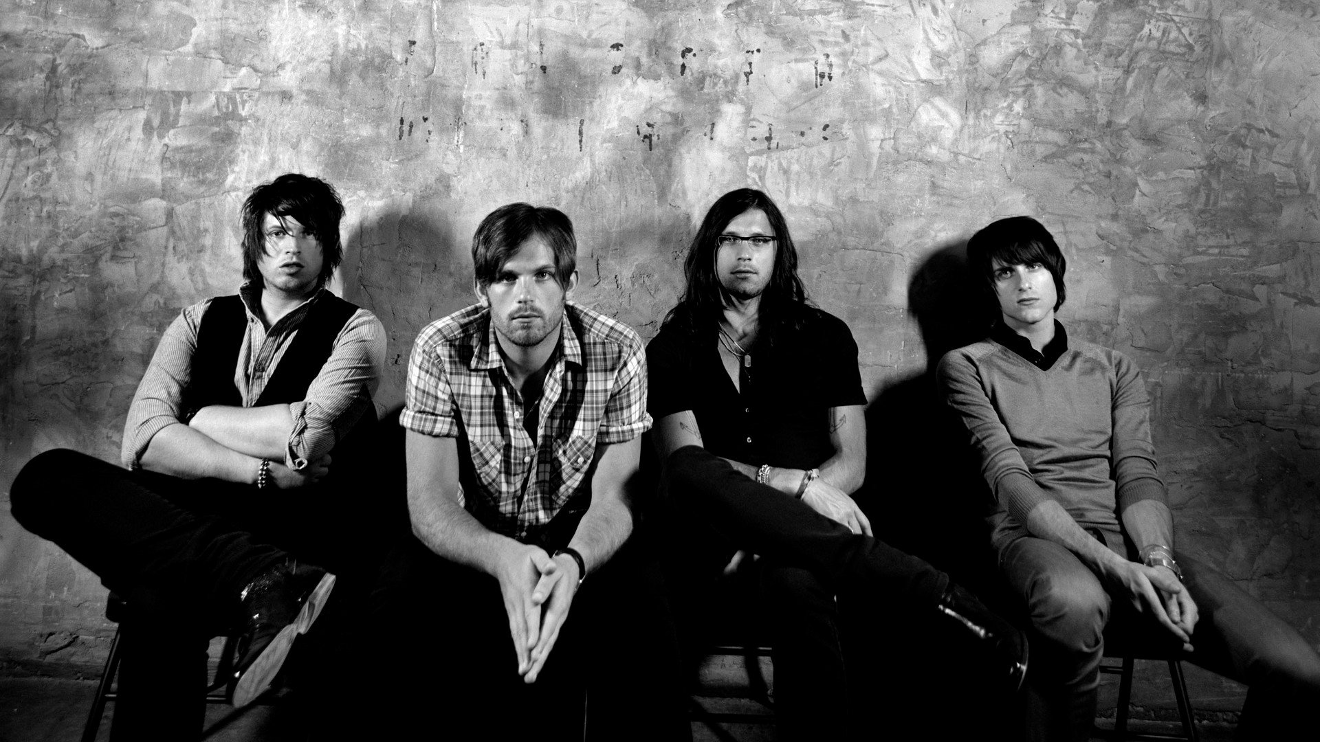 HD desktop wallpaper featuring the members of the band Kings Of Leon against a textured backdrop in monochrome.