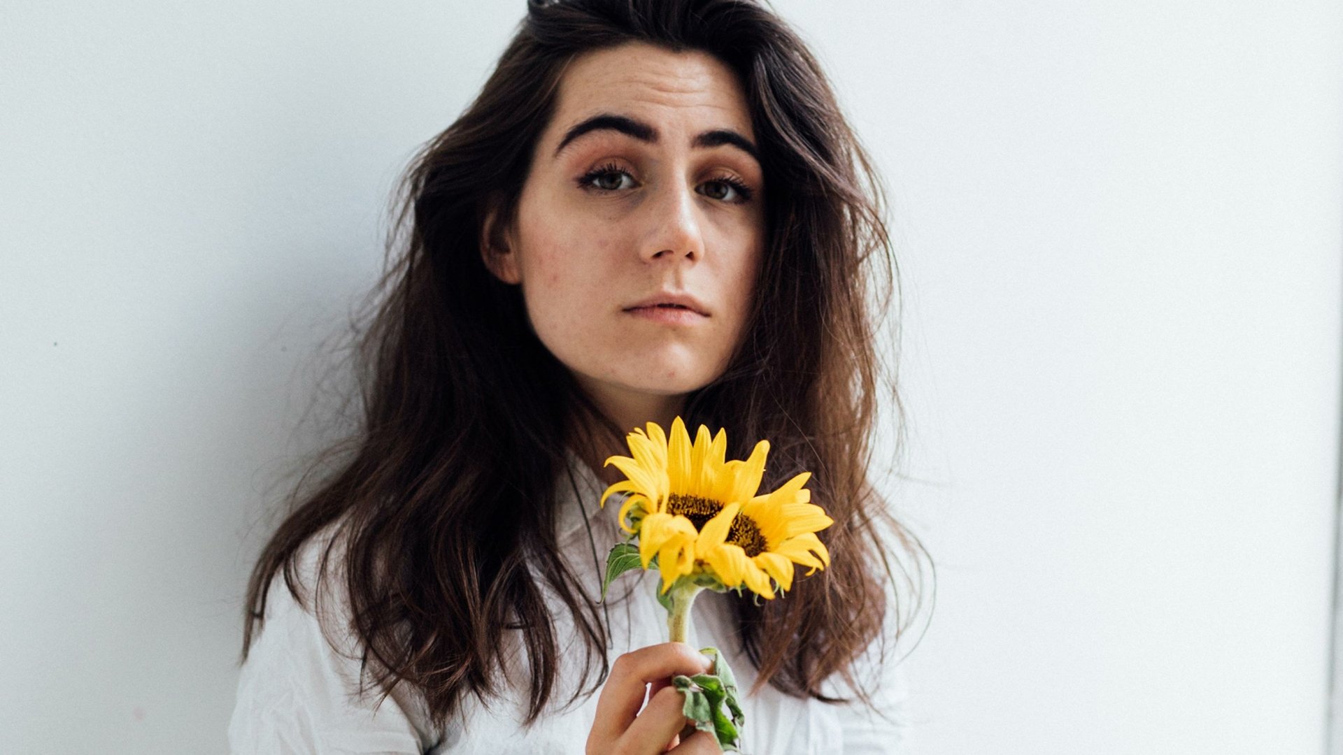 HD desktop wallpaper featuring a person with dark hair holding yellow flowers, providing a clean and vibrant background.