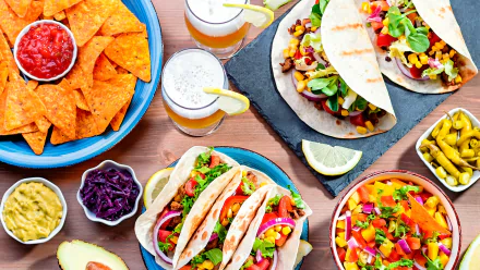 HD desktop wallpaper featuring a vibrant Mexican meal with tacos, nachos, and drinks.