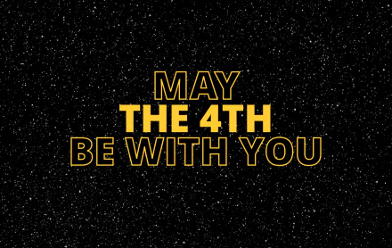 HD desktop wallpaper featuring the phrase May the 4th Be With You in bold yellow letters on a starry space background, celebrating Star Wars Day.