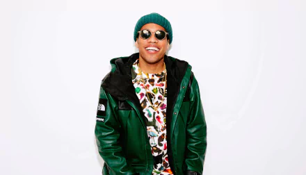 HD wallpaper of a smiling person in a green jacket and beanie, standing against a white background, tagged with Anderson .Paak.