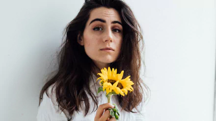 HD desktop wallpaper featuring a person with dark hair holding yellow flowers, providing a clean and vibrant background.