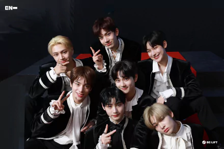 A vibrant HD desktop wallpaper featuring the K-pop group ENHYPEN, showcasing the members smiling and posing together against a sleek black background.