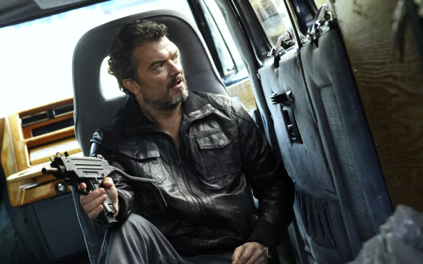 HD desktop wallpaper from Snabba Cash featuring a man holding a gun seated inside a vehicle with a tense expression.