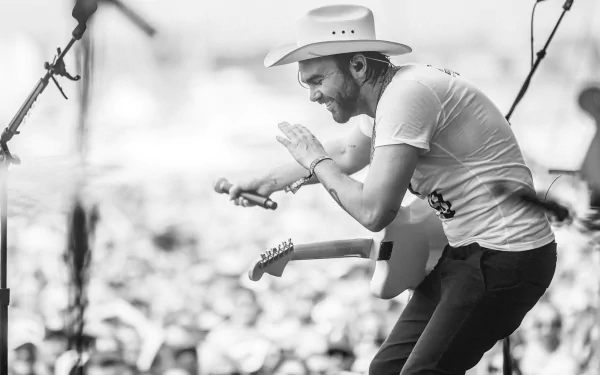 HD wallpaper featuring Shakey Graves performing live, passionately playing guitar in a hat, in monochrome.
