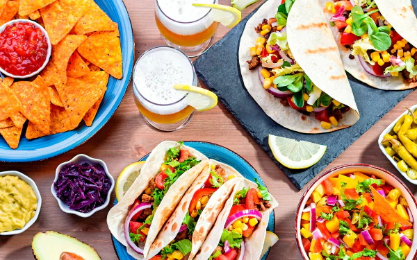 HD desktop wallpaper featuring a vibrant Mexican meal with tacos, nachos, and drinks.