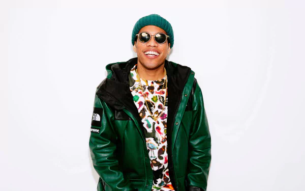 HD wallpaper of a smiling person in a green jacket and beanie, standing against a white background, tagged with Anderson .Paak.