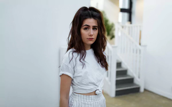 HD wallpaper featuring a stylish individual with brown hair standing in front of a minimalist staircase, tagged as dodie.