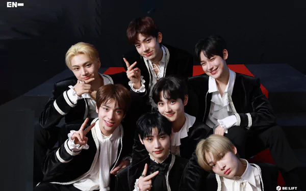 A vibrant HD desktop wallpaper featuring the K-pop group ENHYPEN, showcasing the members smiling and posing together against a sleek black background.