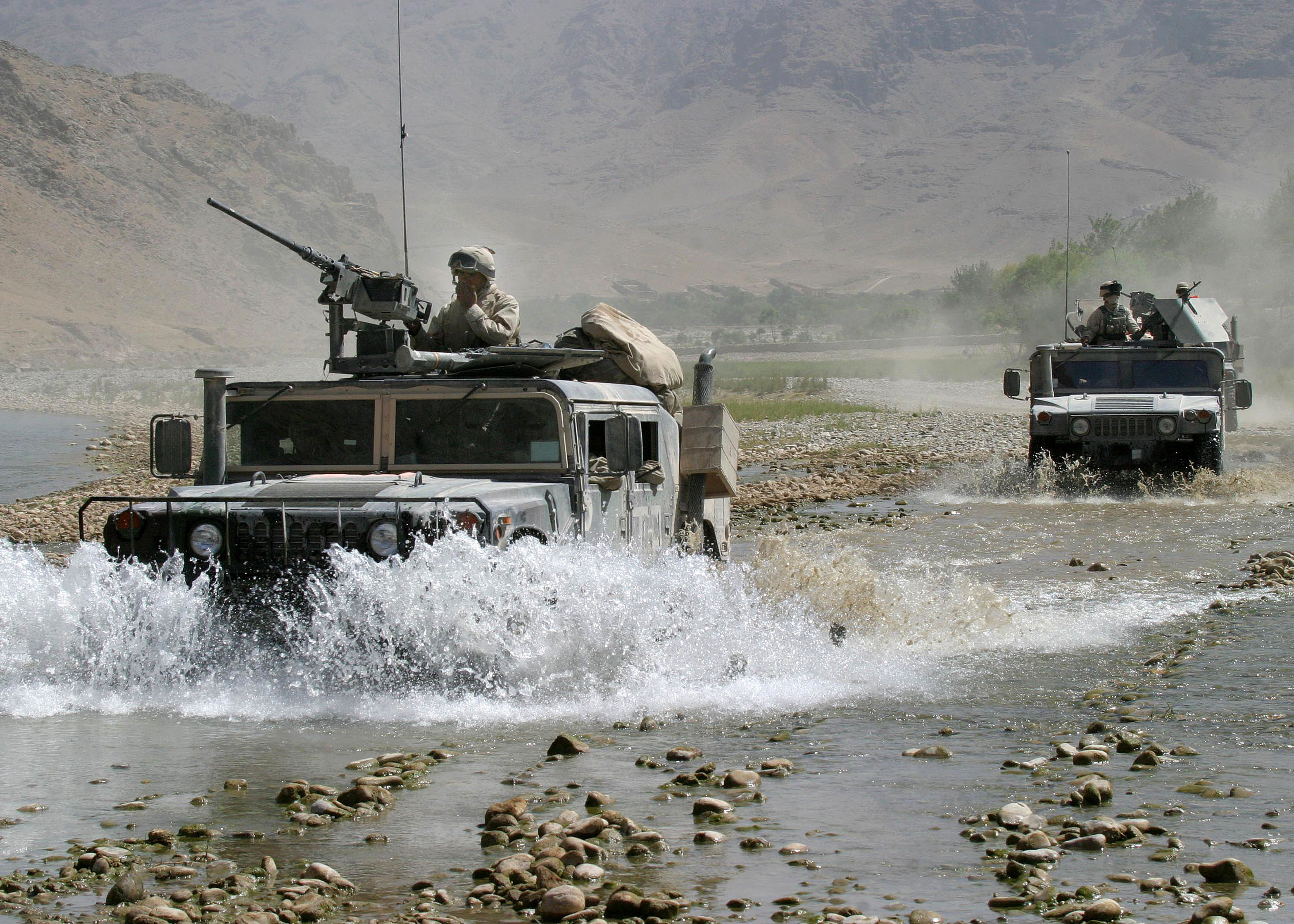 Military vehicle speeding across rugged terrain.