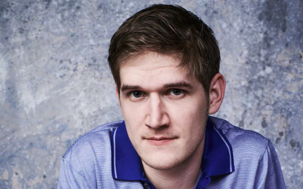 HD desktop wallpaper of a man in a blue shirt against a textured gray background.