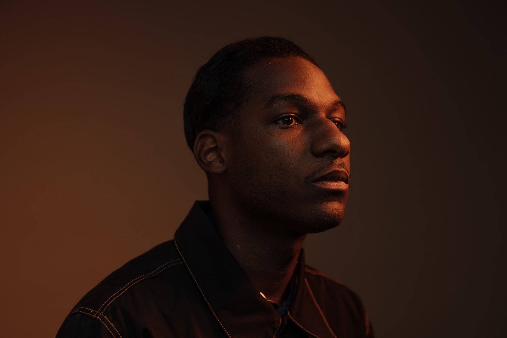 High-definition desktop wallpaper featuring a silhouette profile view of a man with soft lighting on his face against a neutral background, tagged with Leon Bridges.