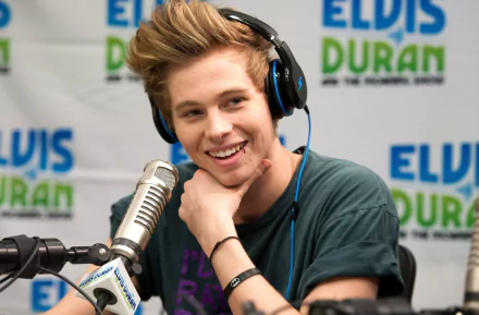 Smiling young man with headphones speaking into a microphone for a HD desktop wallpaper background.