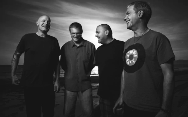 Black and white HD wallpaper featuring four smiling men standing together on a beach at sunset, evoking themes associated with the Descendents.
