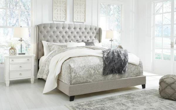 Chic bedroom featuring a plush upholstered bed, serene color palette, and elegant furnishings, set in a bright space with large windows, creating a soothing atmosphere for an HD desktop wallpaper.
