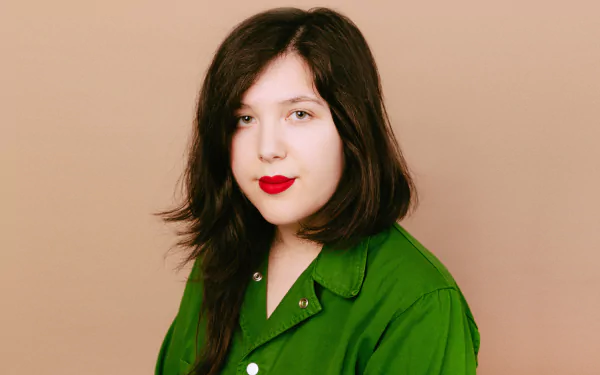 HD desktop wallpaper featuring a person with shoulder-length hair and red lipstick wearing a green shirt against a tan background