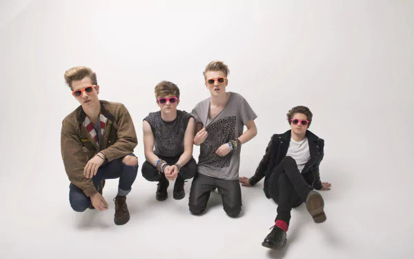 HD desktop wallpaper featuring The Vamps, a four-member band, posing stylishly in colorful sunglasses against a minimalist white background.