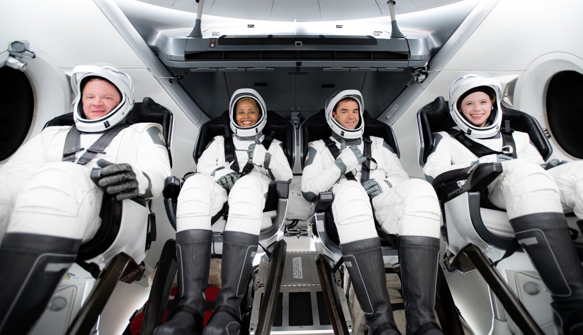 HD wallpaper of Inspiration4 civilian astronaut crew in space suits seated inside spacecraft for desktop background.