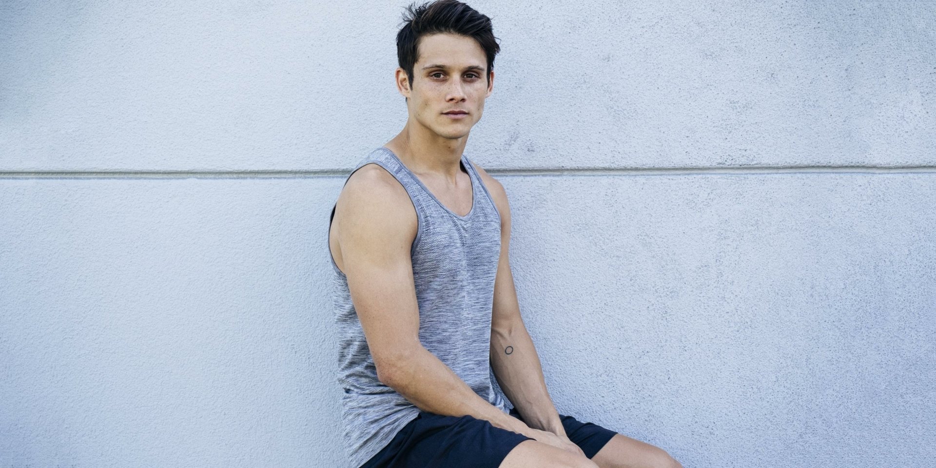 HD desktop wallpaper featuring a posed individual sitting against a wall, creating a stylish background.