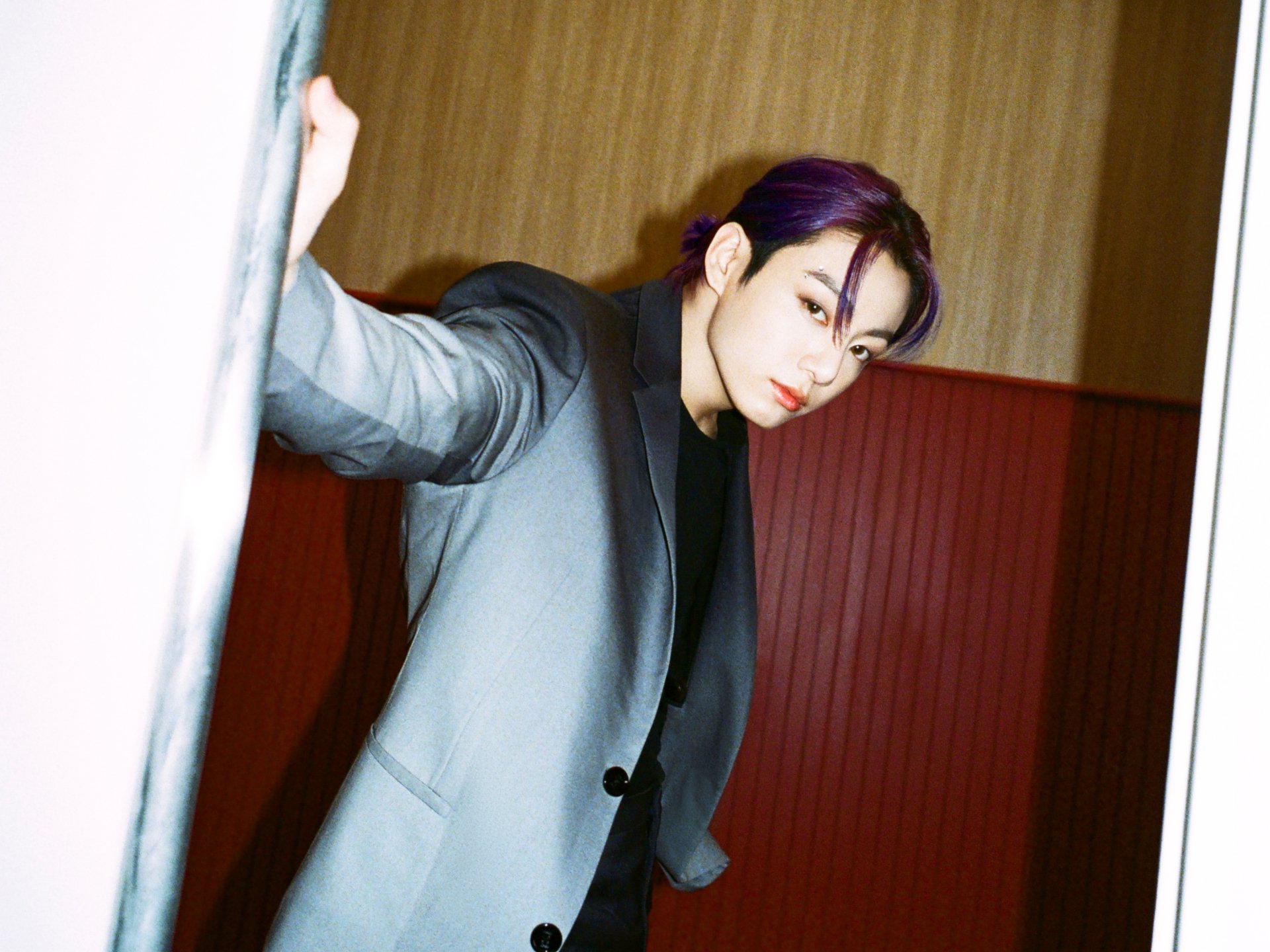 HD desktop wallpaper featuring Jungkook, the K-pop singer from BTS, dressed in a sleek suit against a warm-toned background.