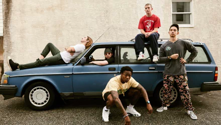 HD wallpaper of five people casually posed with an old blue car, presenting a relaxed and stylish vibe for a desktop background.