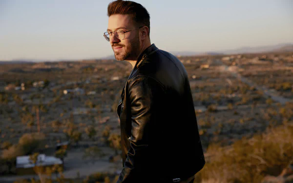 Stylish man in leather jacket standing with a scenic overlook at sunset, HD desktop wallpaper and background.