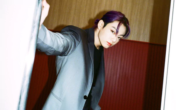 HD desktop wallpaper featuring Jungkook, the K-pop singer from BTS, dressed in a sleek suit against a warm-toned background.