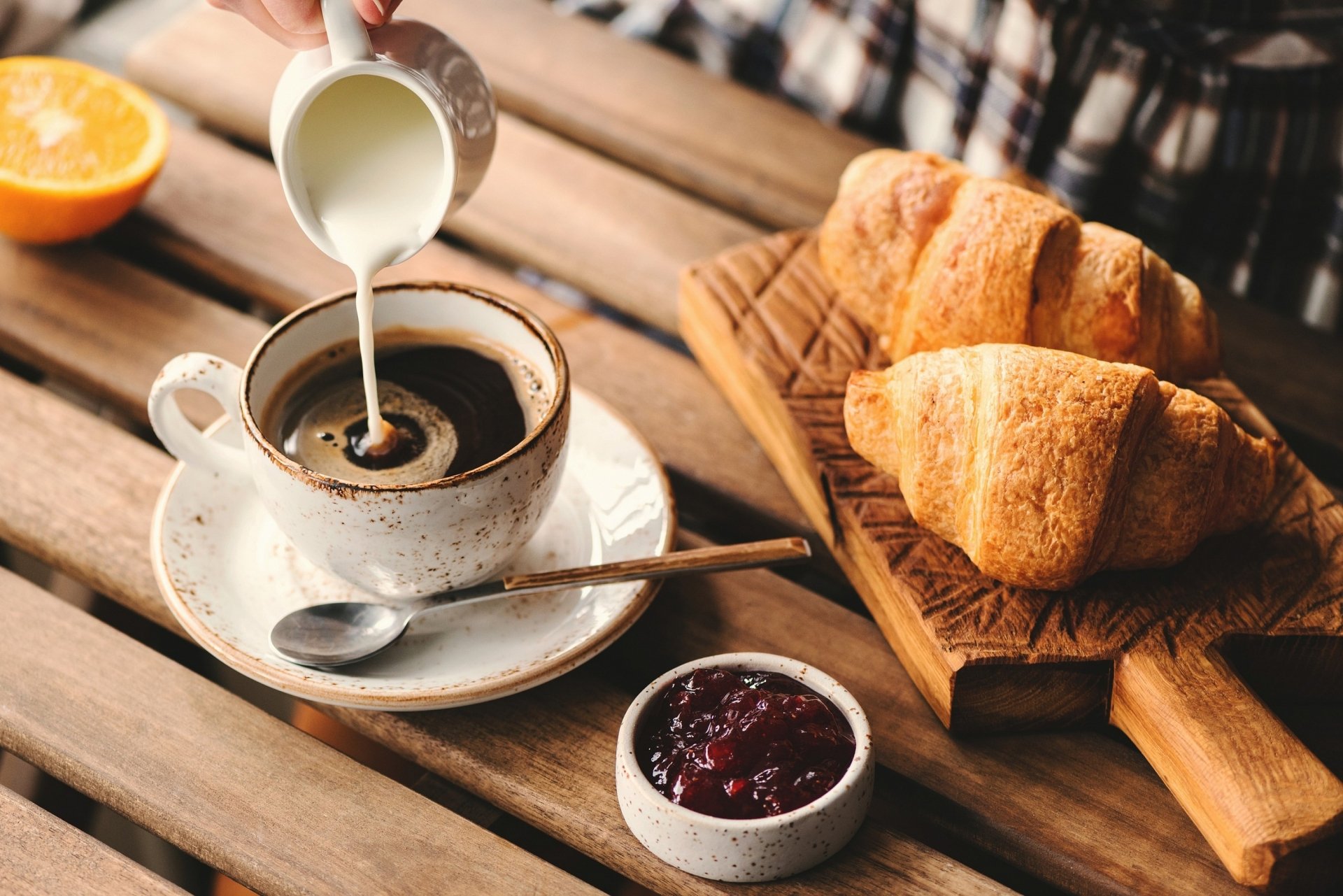 2K Quad HD PC desktop wallpaper/background: breakfast food and drink — coffee being creamed, croissants on a board, orange half and jam.