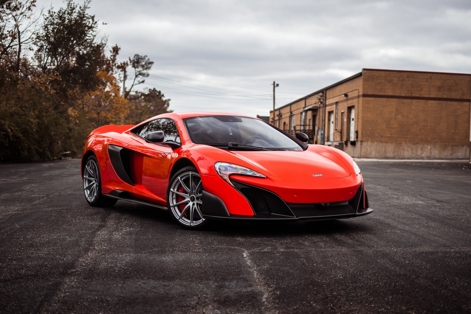 Red McLaren 675LT supercar parked on asphalt in an urban lot — HD PC desktop wallpaper background showcasing the vehicle.