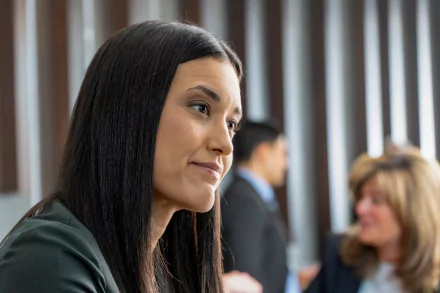 Profile of a woman with long dark hair from TV show Dexter: New Blood, subtle smile in a blurred office scene — 2K Quad HD PC desktop wallpaper