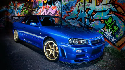 Blue Nissan Skyline R34 parked in front of colorful graffiti art, HD wallpaper for desktop background.
