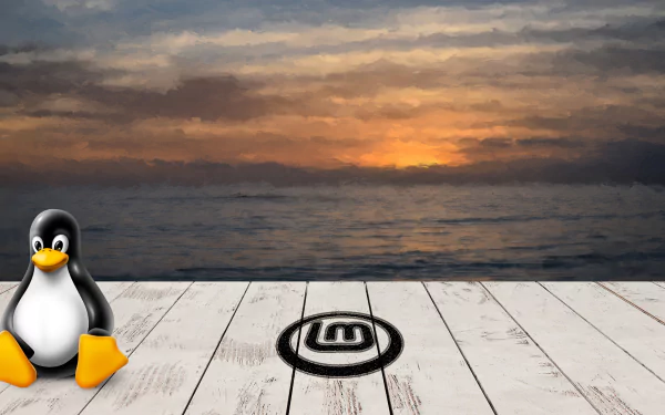 2K Quad HD PC desktop wallpaper showing a Linux Mint technology theme: Tux penguin on white wooden planks with the Linux Mint logo stenciled, sunset over the ocean.