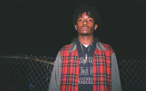 A striking HD desktop wallpaper featuring Playboi Carti, captured at night with a moody backdrop, showcasing his unique style and presence.