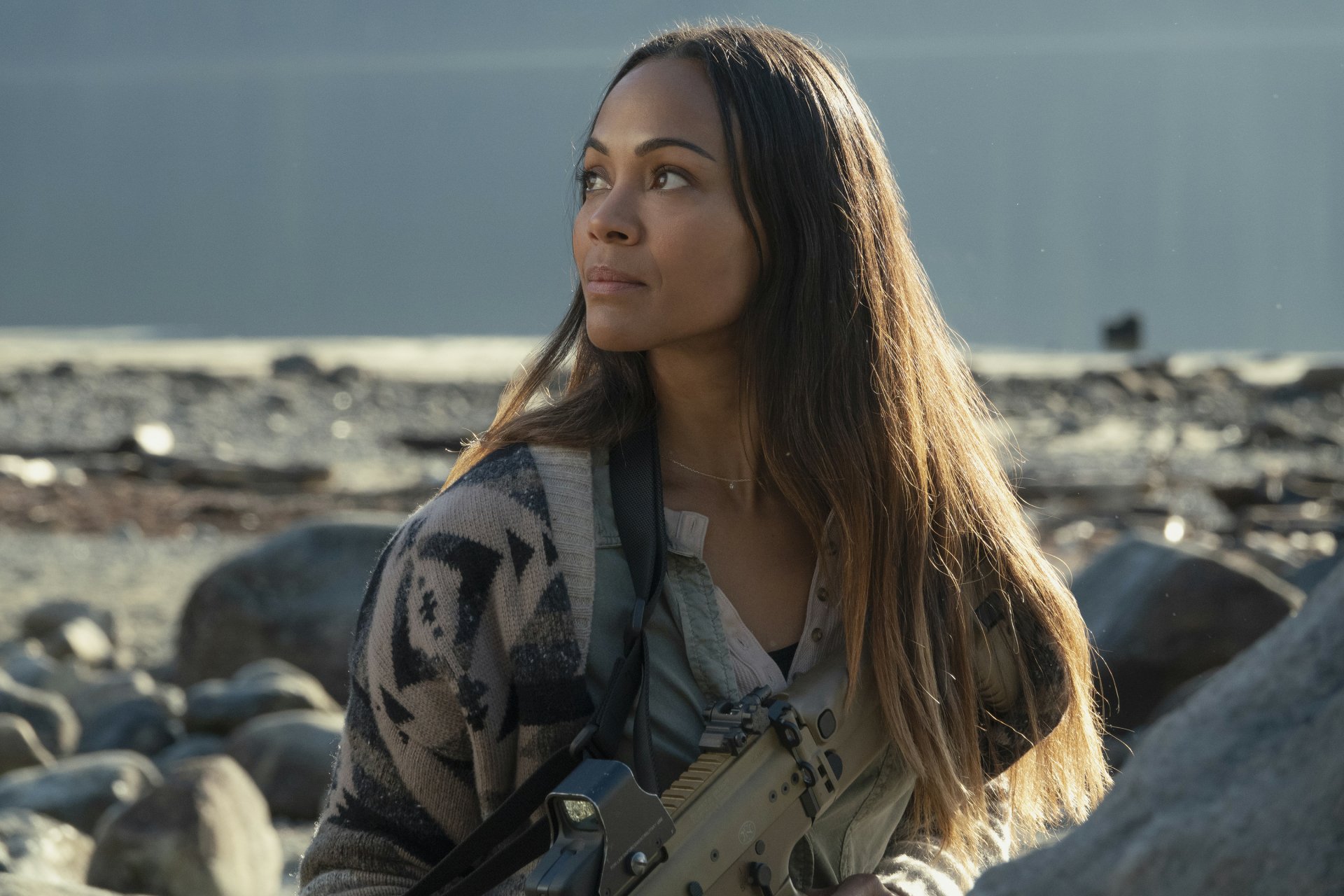 Zoe Saldana in a scene from the movie The Adam Project, featured in an HD PC desktop wallpaper with a rocky outdoor background.