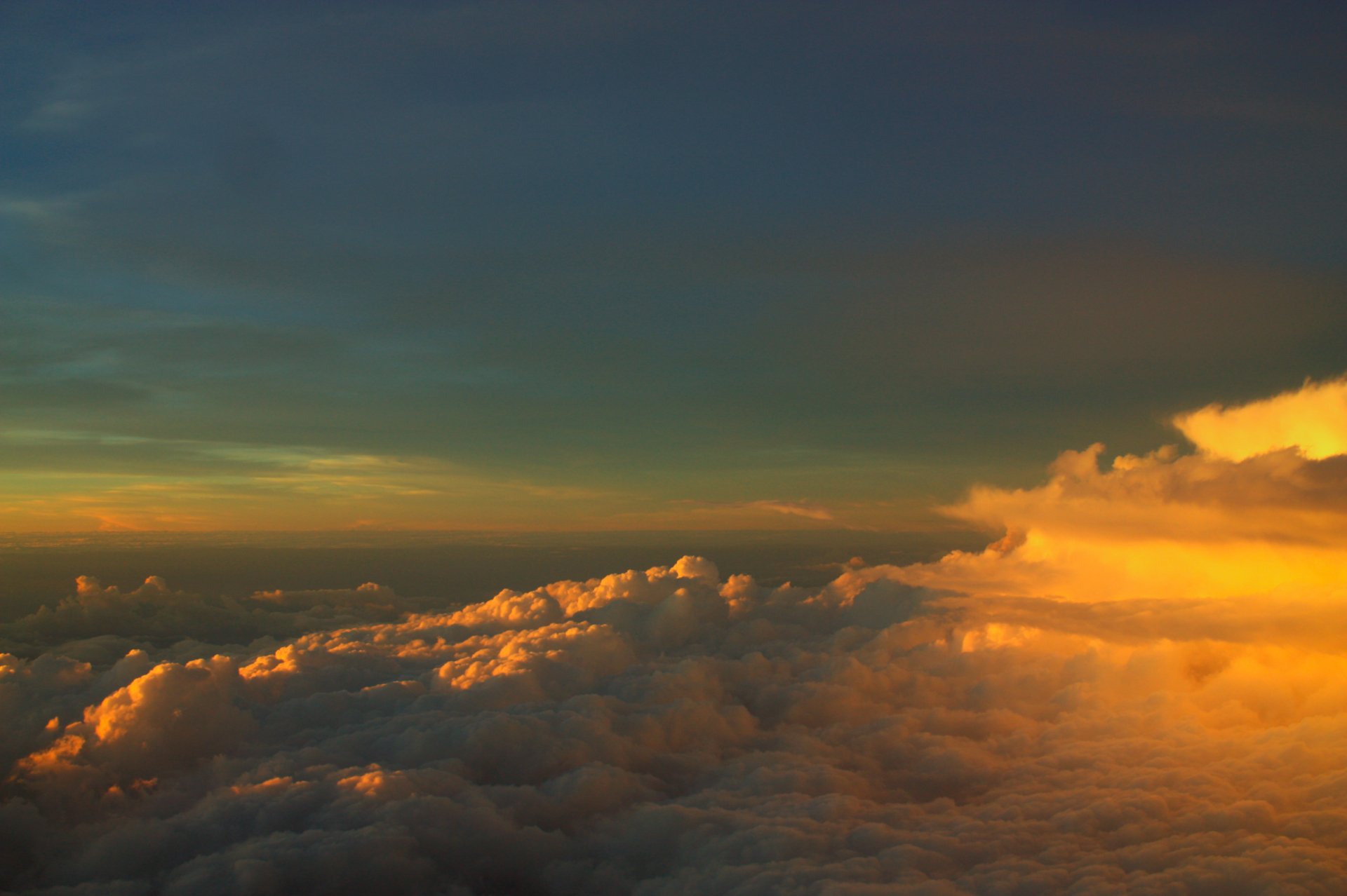 2K Quad HD PC desktop wallpaper and background — nature cloud panorama: golden sunlight on billowing clouds beneath a deep blue sky at sunset.