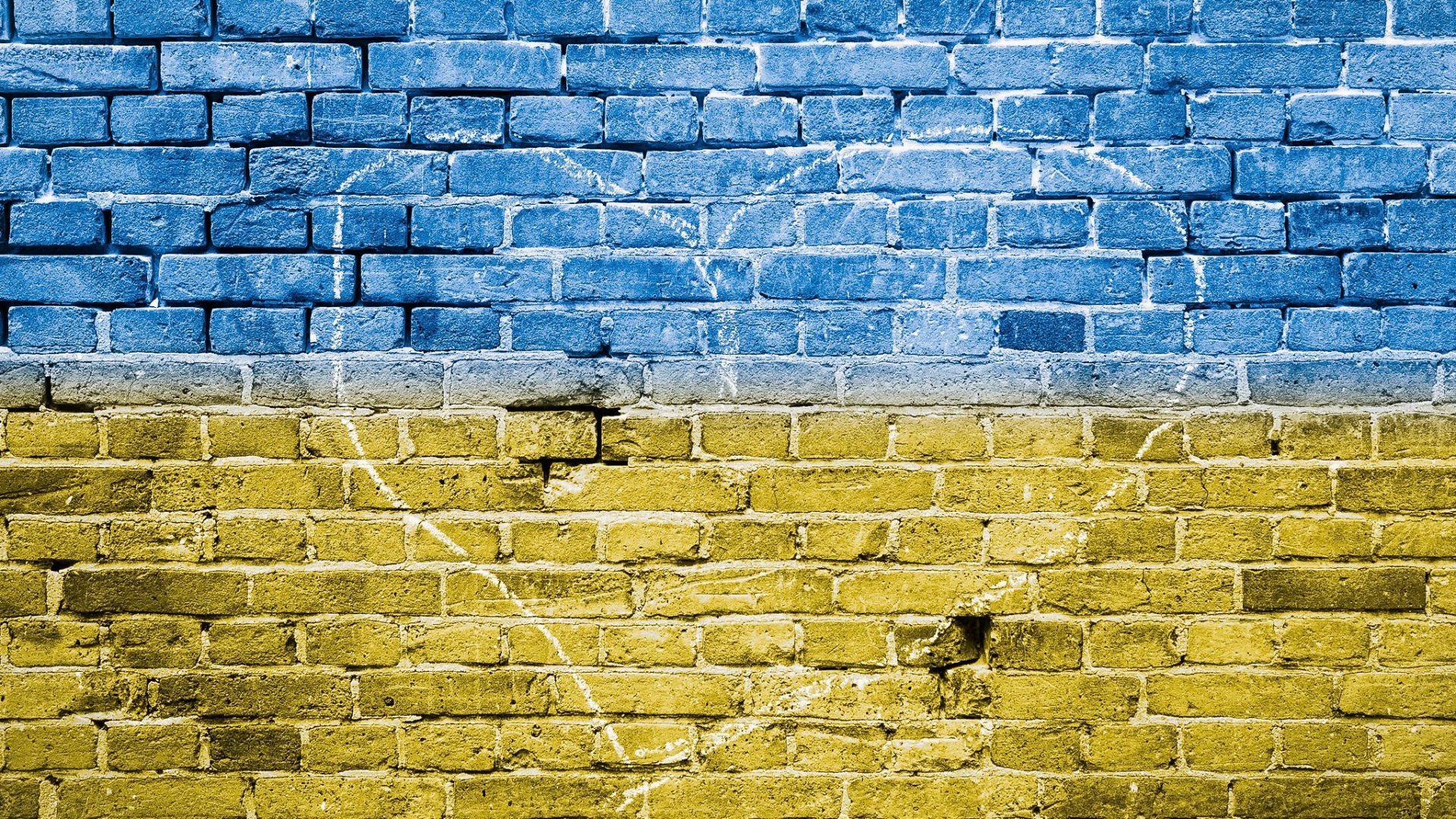 HD PC desktop wallpaper showing the flag of Ukraine painted on a weathered brick wall — blue over yellow textured background.