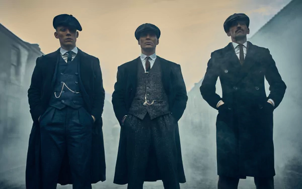 HD wallpaper of Cillian Murphy as Thomas Shelby from the TV show Peaky Blinders, featuring three men in period attire standing confidently in a misty street.